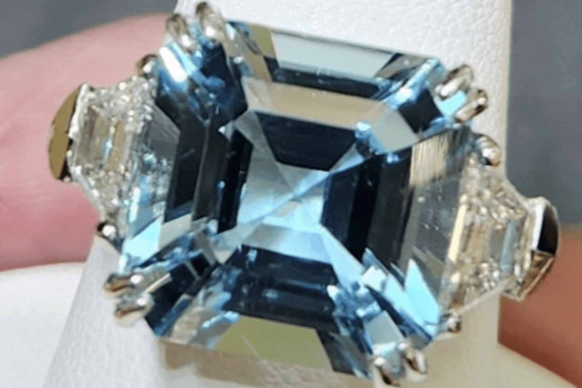 A large aquamarine ring with diamond accents on a finger display stand (1) A large aquamarine ring with diamond accents on a finger display stand